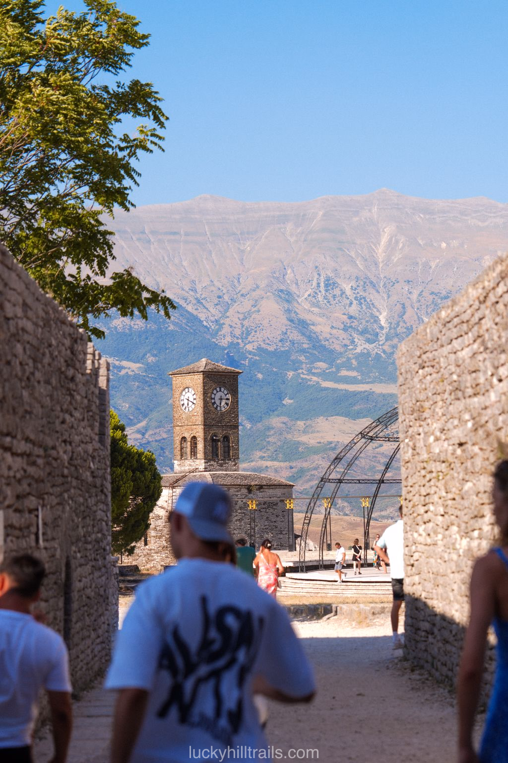 A clock tower inside Gjirokastër Castle between stone walls with mountain views