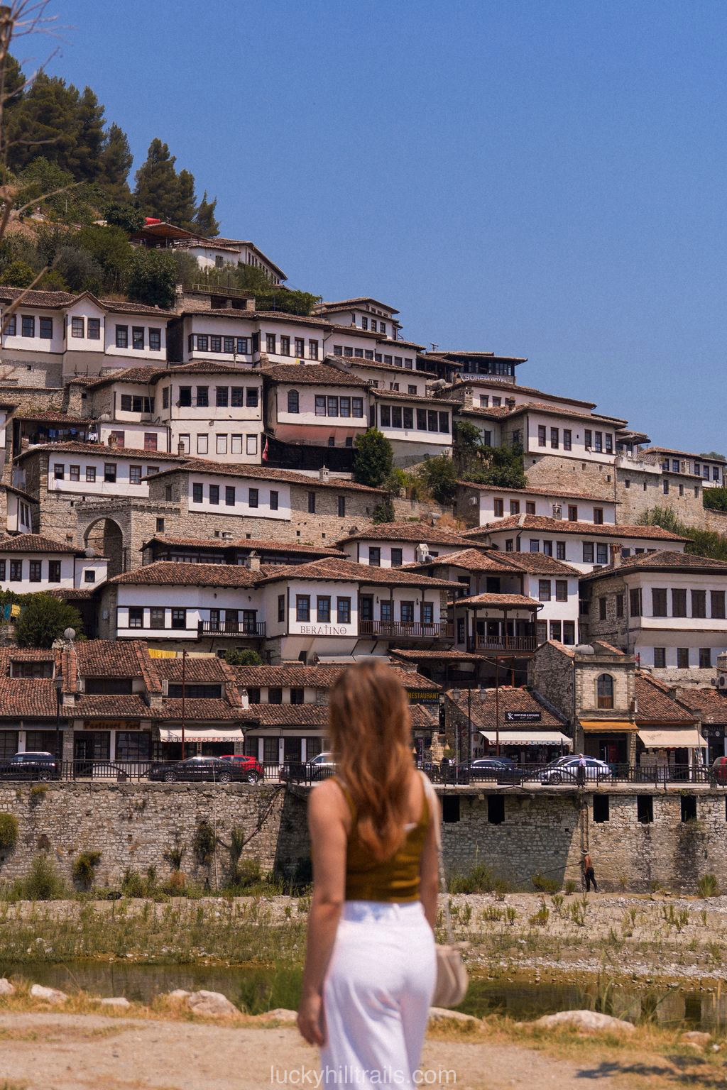 A girl admiring the panorama of Berat — houses with large windows cover the hillside