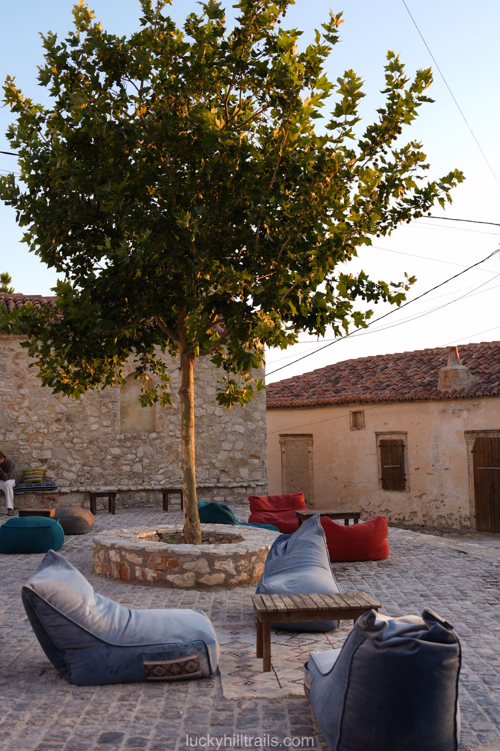 Terrace of Aman bar with bean bag chairs around a tree in a stone courtyard