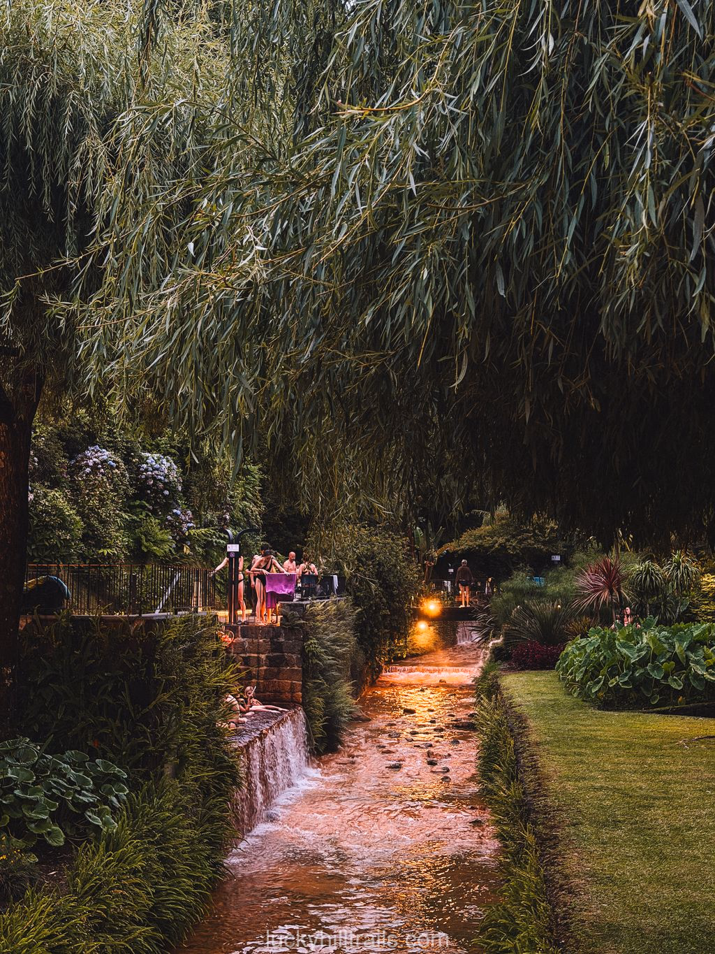 Illuminated thermal stream flowing through the pools of Poça da Dona Beija at night, São Miguel, Azores