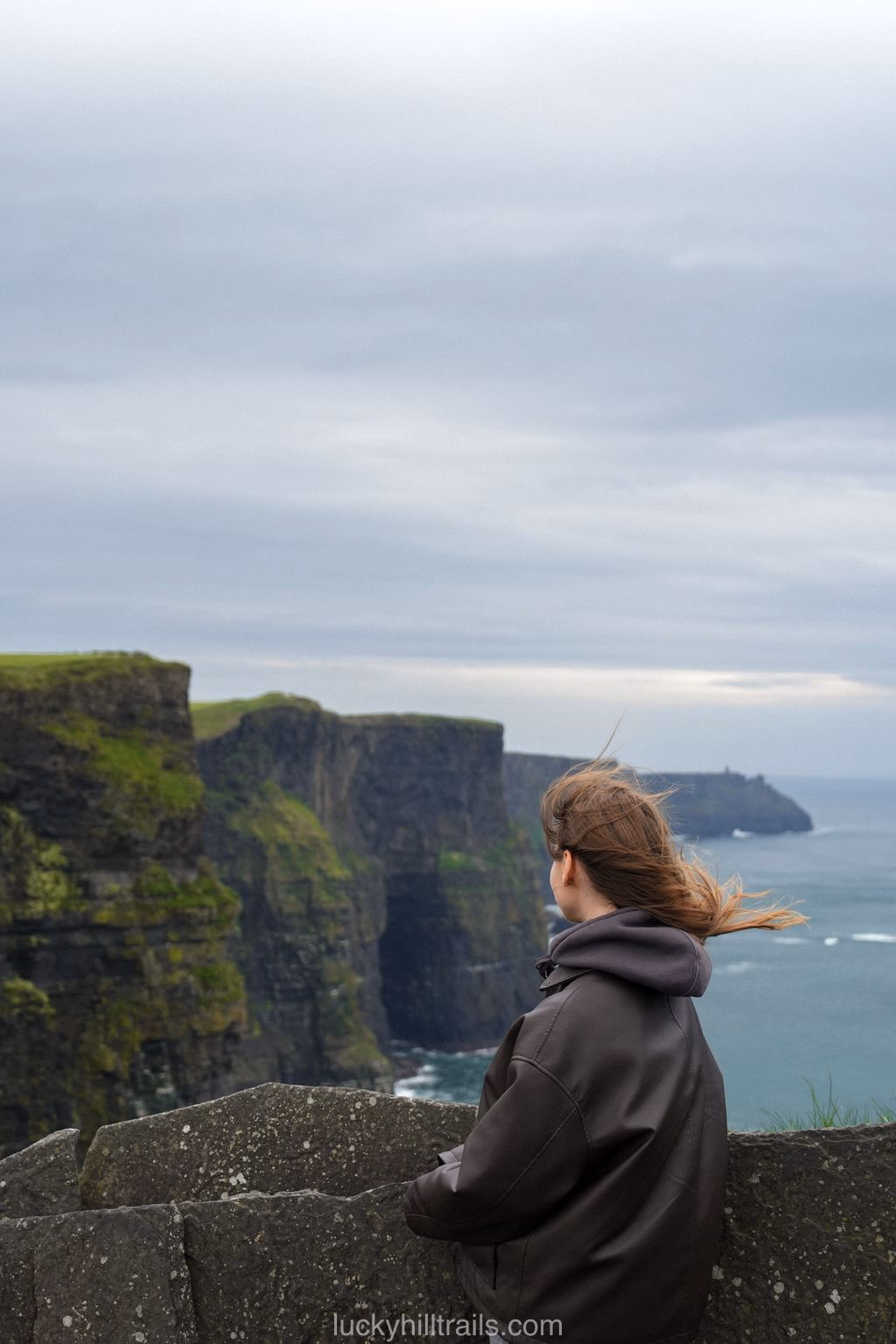 A visitor looks out at the vertical Cliffs of Moher above the Atlantic from the official viewing area, Clare, Ireland