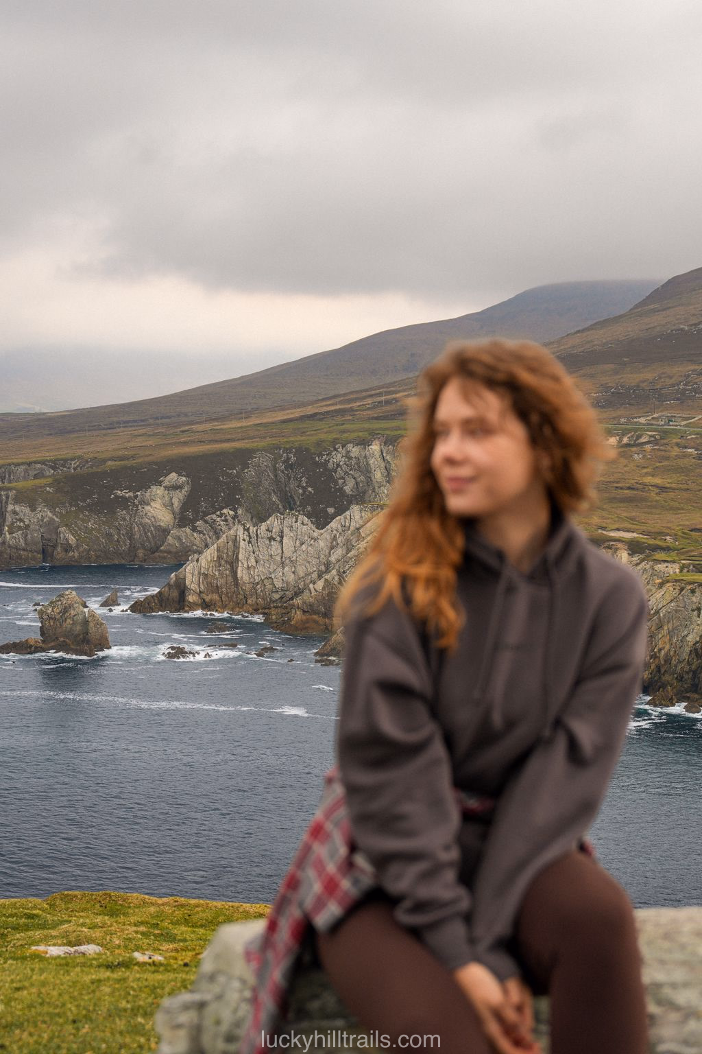 A girl against the white Ashleam cliffs above the dark ocean, Achill Island, County Mayo, Ireland