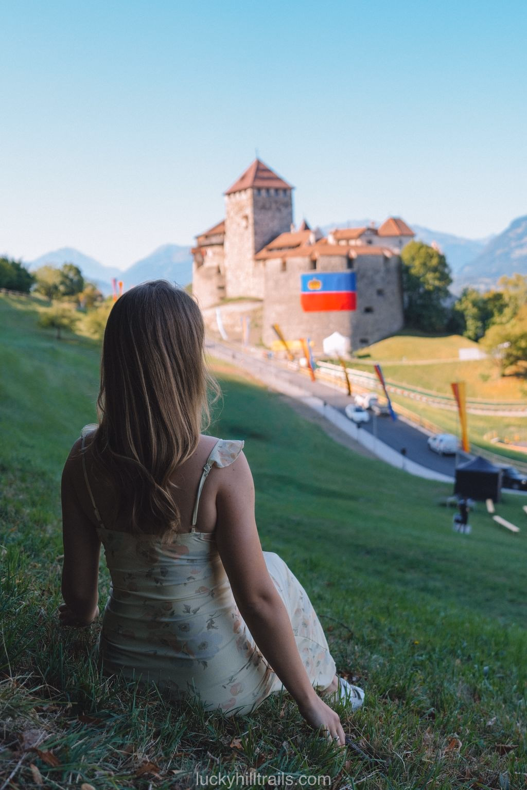 Woman sitting on the grass looking at Vaduz Castle