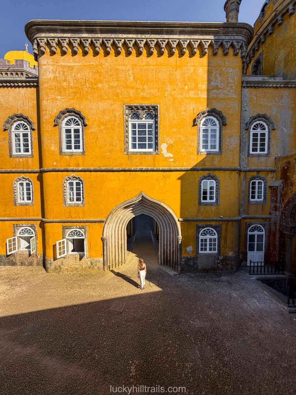 Yellow inner courtyard of Pena Palace with a Moorish arch – a girl standing in the gateway, Sintra, Portugal