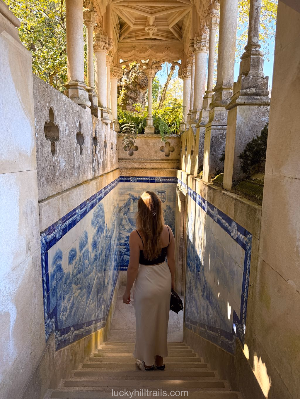 Loggia de Pisões at Quinta da Regaleira – a stone gallery with columns and blue azulejo panels, a girl descending the stairs, Sintra, Portugal